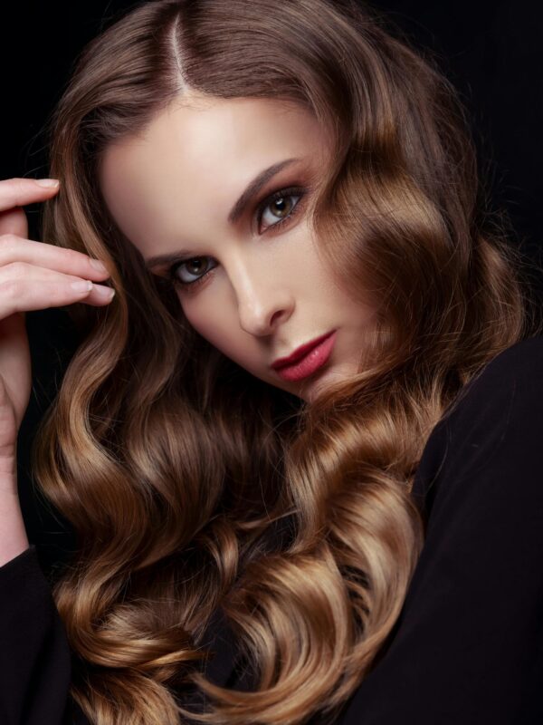 Elegant brunette woman in a close-up fashion portrait with stunning wavy hair and makeup.